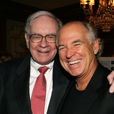 Warren Buffett has his hand around Jimmy Buffett's shoulder as they are smiling in the pic.